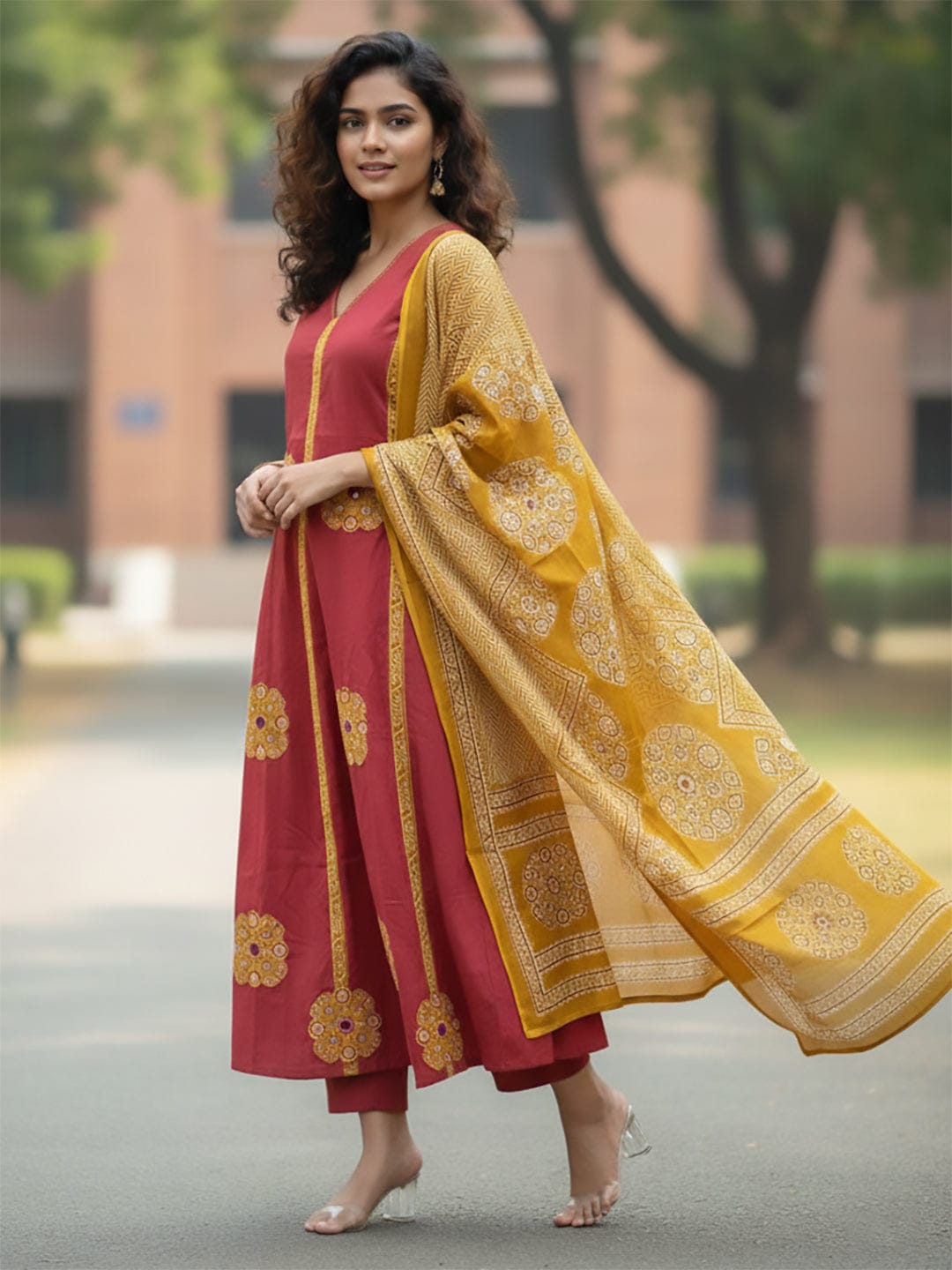 Rust Anarkali kurta set featuring multicolour buta prints, embroidered V-neck and sleeves, paired with solid straight-fit trousers and a tasselled dupatta.